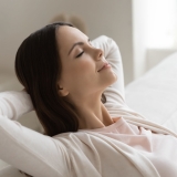 Weekend, at least!.. Tranquil peaceful millennial female enjoying freedom napping dreaming relaxing on couch with closed eyes and hands behind head meditating breathing fresh air feeling happy serene