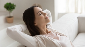 Weekend, at least!.. Tranquil peaceful millennial female enjoying freedom napping dreaming relaxing on couch with closed eyes and hands behind head meditating breathing fresh air feeling happy serene