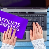 woman hands on laptop and Affiliate marketing words on paper sheet