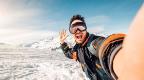 Happy skier taking a selfie on the mountains - Young man having fun skiing downhill in winter forest